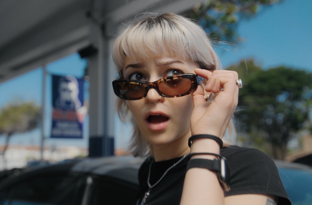 Emmy pulls down her sunglasses, looking shocked.